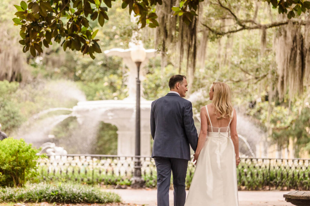 Why Savannah is the best place to elope in the south - a couple walks towards Forsyth fountain on their elopement day