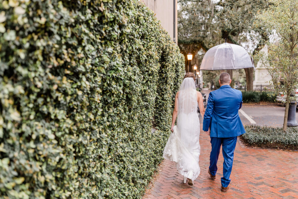 What happens if it rains on your Savannah wedding day | Couple holding clear umbrella on brick sidewalk